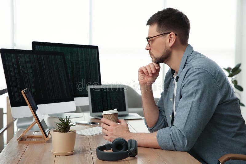 Programmer with coffee working at desk stock photography