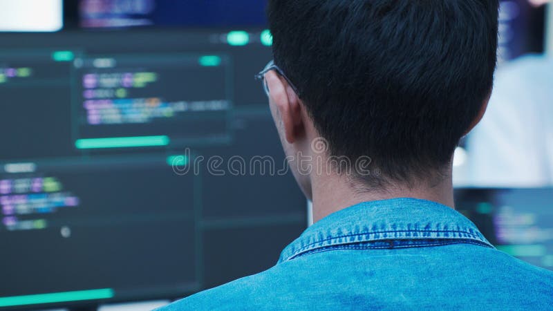 Programmer developing software and analyzing source code on computer screens in a technology workspace programmer coding software