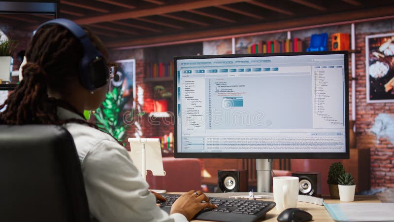Programmer wearing headphones types code into PC, developing software programs, entering commands. Woman at home fixing errors in application, implementing new features, listening music, camera A. Developing programmer stock images, royalty-free photos and pictures