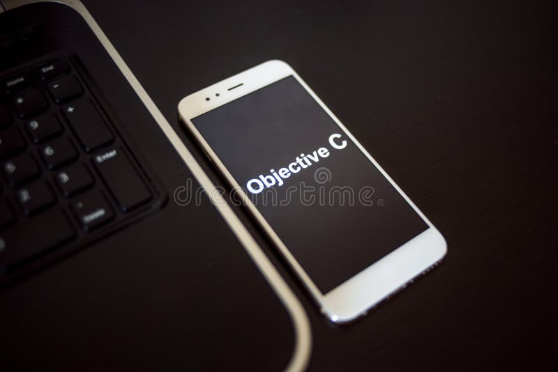 Programming language Objective C for mobile development, concept. Smartphone near the laptop royalty free stock photo