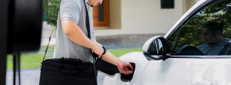 Progressive asian man recharge his EV car at home charging station.
