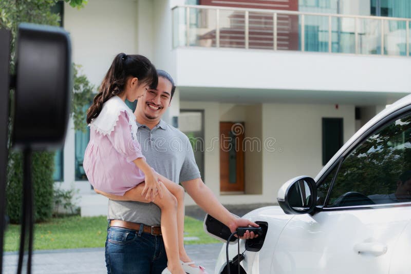 Progressive concept of father and daughter with EV car and home charging station