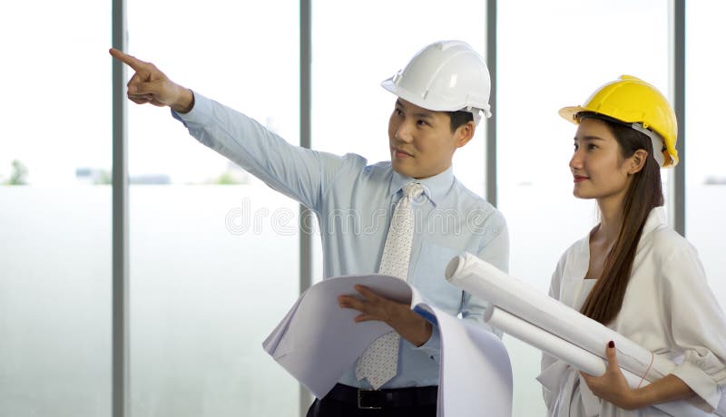 The project owner and the assistant wear protective hats checking the projects that are under construction. The woman hold the stock images
