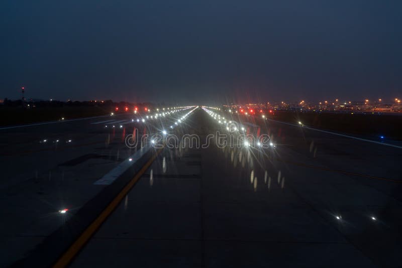 Projecteurs d'atterrissage SUR une piste d'aéroport au ciel nocturne image libre de droits Projecteurs d'atterrissage SUR une piste d'aéroport au ciel nocturne image libre de droits