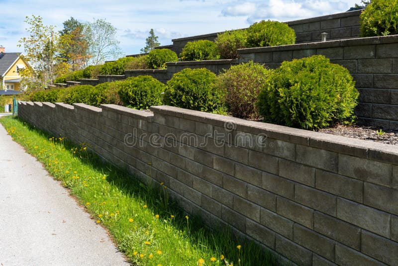 Projektowanie krajobrazu ogrodowego. mur dekoracyjny z bloczków ciemnoszare lub betonowych cegieł cementowych. ogród ozdobny obcię
