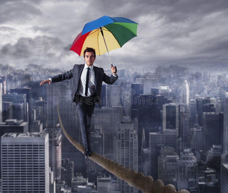 Promenade d'homme d'affaires d'Equilibrist sur une corde avec le parapluie au-dessus de la ville Le concept de surmontent les pro images stock Promenade d'homme d'affaires d'Equilibrist sur une corde avec le parapluie au-dessus de la ville Le concept de surmontent les pro images stock