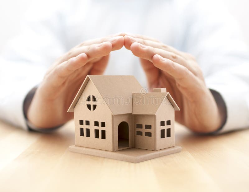 Property insurance. House miniature covered by hands.