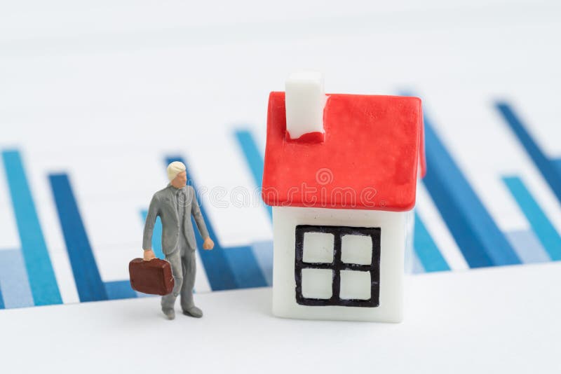 Property, real estate or Reits price analysis concept, miniature businessman with small house on yearly chart and graph reports stock images Property, real estate or Reits price analysis concept, miniature businessman with small house on yearly chart and graph reports stock images