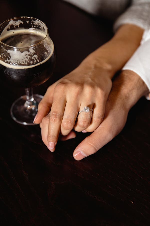 Proposition de vie réelle : Couplez tenir des mains dans un bar avec un verre de bière à leur côté image libre de droits Proposition de vie réelle : Couplez tenir des mains dans un bar avec un verre de bière à leur côté image libre de droits