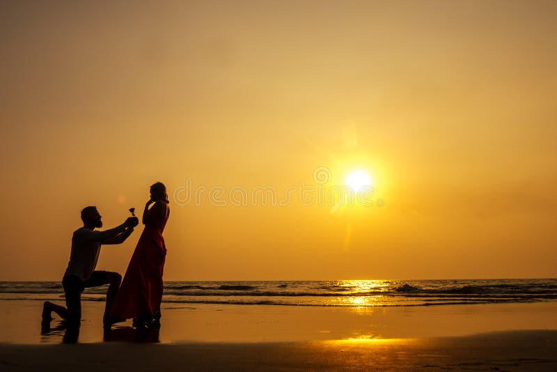 Proposta romantica di matrimonio al mare al tramonto sul mare Una giovane coppia di innamorati ha detto sì all'offerta fotografia stock libera da diritti Proposta romantica di matrimonio al mare al tramonto sul mare Una giovane coppia di innamorati ha detto sì all'offerta fotografia stock libera da diritti