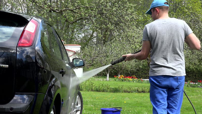Proprietário do carro lava automóvel preto com pressão de água no jardim 4 k