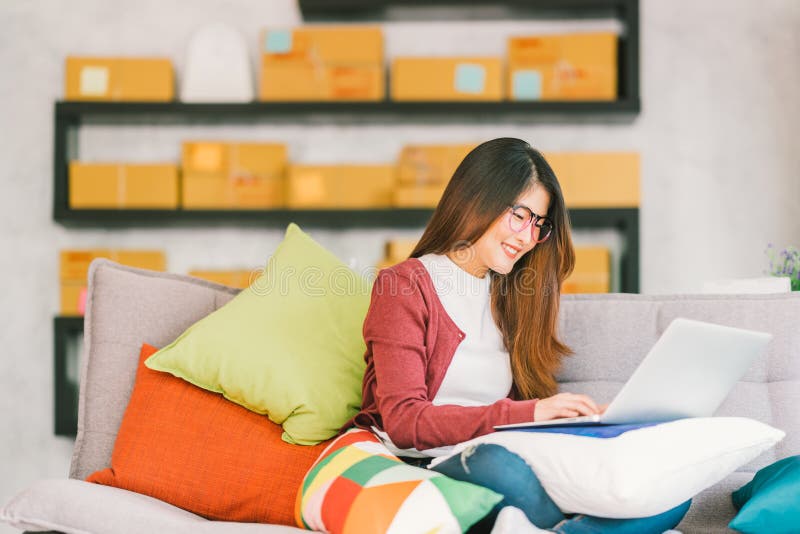 Proprietário empresarial pequeno asiático novo que trabalha no laptop em casa foto de stock