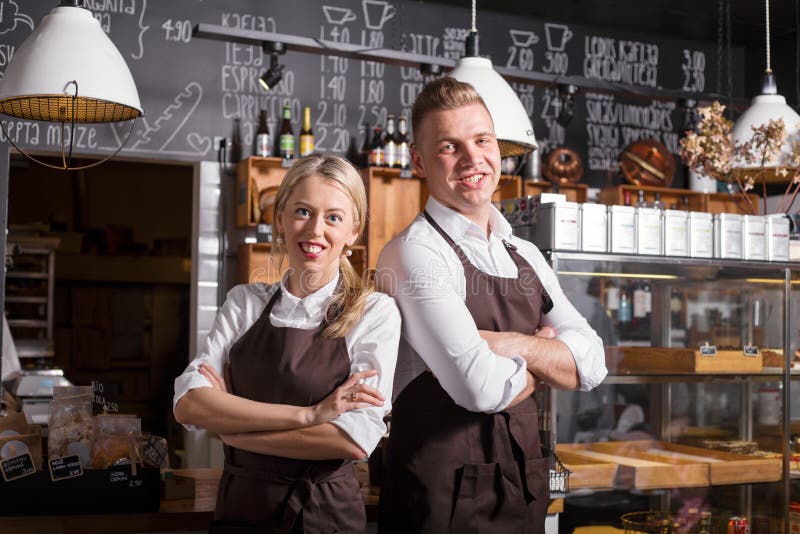 Proprietários de cafetaria que estão com suas mãos cruzadas fotografia de stock Proprietários de cafetaria que estão com suas mãos cruzadas fotografia de stock