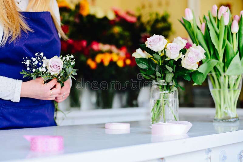 Propriétaire de femme de fleuriste préparant le bouquet des roses roses photographie stock libre de droits Propriétaire de femme de fleuriste préparant le bouquet des roses roses photographie stock libre de droits
