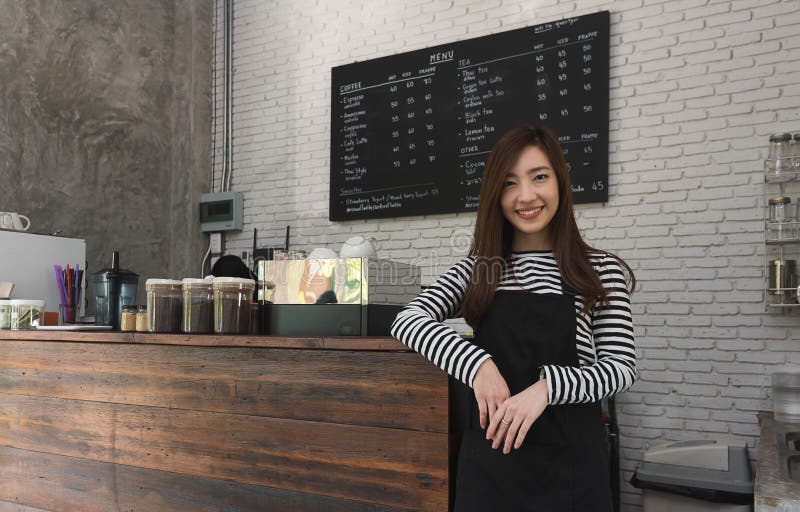 Propriétaire de jeune femme d'un support de café devant le compteur de café, yo photos stock Propriétaire de jeune femme d'un support de café devant le compteur de café, yo photos stock