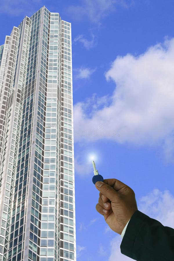 Businessman holding key,concept for real property,just sold,sales,new occupant- in a clear blue sky and high rise tower background. Businessman holding key,concept for real property,just sold,sales,new occupant- in a clear blue sky and high rise tower background.