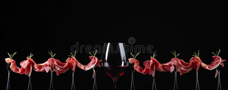 Prosciutto mit Rosmarin und Glas Rotwein auf einem schwarzen backgr lizenzfreie stockbilder Prosciutto mit Rosmarin und Glas Rotwein auf einem schwarzen backgr lizenzfreie stockbilder