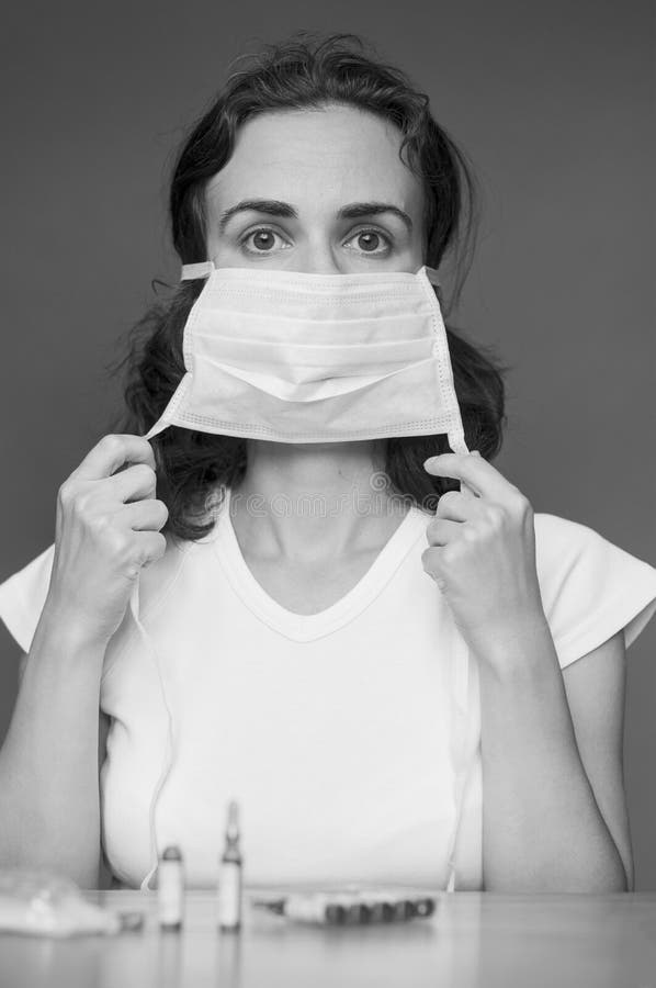 Giovane donna mette un medico maschera per la protezione contro l'influenza.