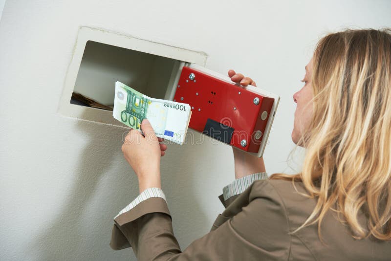 Protection et sécurité d'argent La femme a mis l'argent liquide de l'épargne dans le coffre-fort de mur photographie stock libre de droits Protection et sécurité d'argent La femme a mis l'argent liquide de l'épargne dans le coffre-fort de mur photographie stock libre de droits