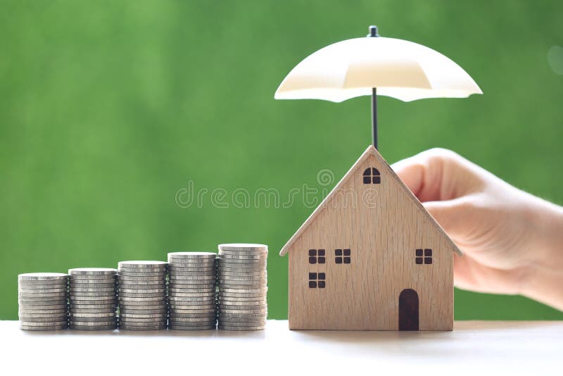 Protection  Stack of coins money and Model house with hand holding the umbrella on natural green background  Finance insurance and