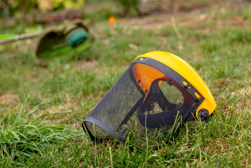 Trimmer for Mowing Grass, Protective Mask and Mittens in the Garden on