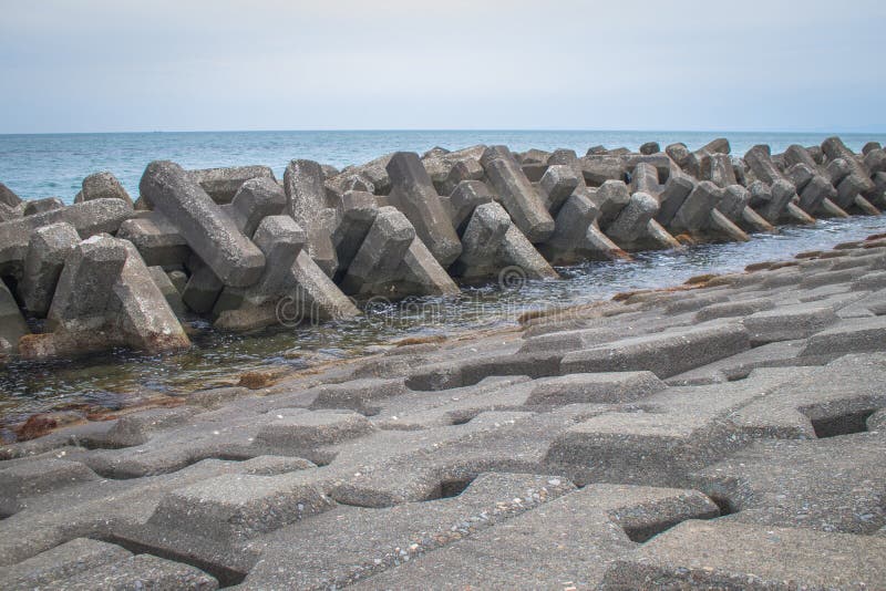 Protezione costiera del frangiflutti costruita dai blocchetti prefabbricati del cemento per ridurre l'intensità di azione dell'on fotografie stock Protezione costiera del frangiflutti costruita dai blocchetti prefabbricati del cemento per ridurre l'intensità di azione dell'on fotografie stock