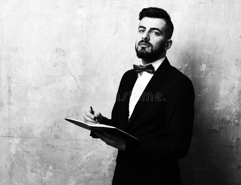 Proud and assured young employer with beard writes in organizer stock photo Proud and assured young employer with beard writes in organizer stock photo