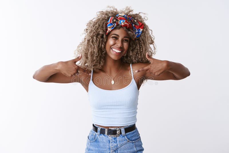 Proud and happy, delighted of herself attractive african-american blond curly-haired young woman with headband, pointing stock photo Proud and happy, delighted of herself attractive african-american blond curly-haired young woman with headband, pointing stock photo