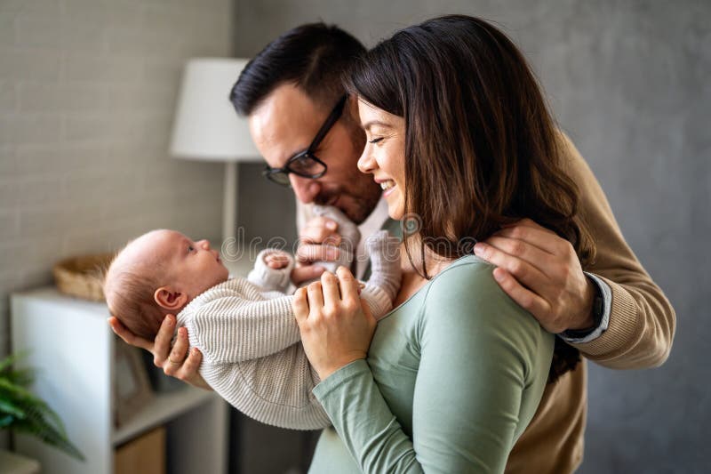 Proud mother and father smiling at their newborn baby daughter, son at home stock photo