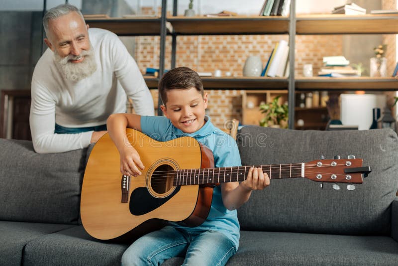Grandfather watching his grandson play guitar royalty free stock image Grandfather watching his grandson play guitar royalty free stock image