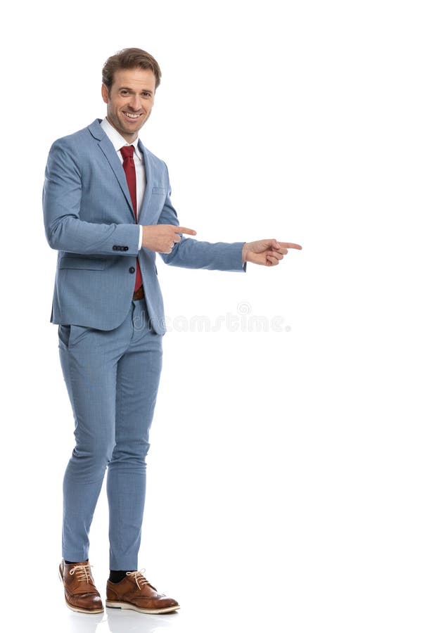 Proud young businessman in blue suit smiling and pointing finger to side