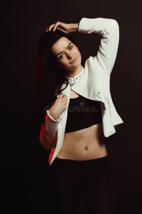 Prova di modello con il modello abbronzato adorabile in rivestimento alla moda sopra un bla fotografie stock Prova di modello con il modello abbronzato adorabile in rivestimento alla moda sopra un bla fotografie stock