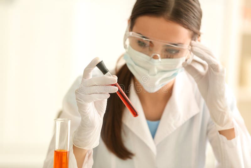 Provetta femminile della tenuta dello scienziato con il campione di colore in laboratorio fotografia stock Provetta femminile della tenuta dello scienziato con il campione di colore in laboratorio fotografia stock