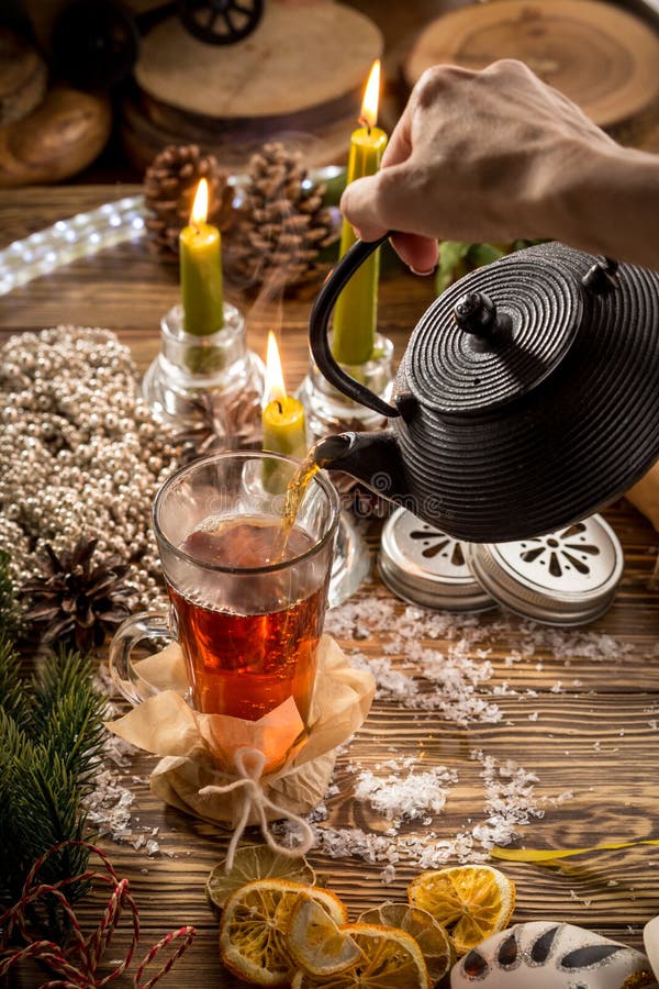 Prozess des Gießens des Tees in die Glasschale auf Holztisch auf Weihnachten verziertem Hintergrund lizenzfreie stockfotos Prozess des Gießens des Tees in die Glasschale auf Holztisch auf Weihnachten verziertem Hintergrund lizenzfreie stockfotos