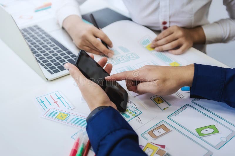 Prueba de dos programadores que cifra tecnologías con el teléfono móvil para comparar página web móvil y de escritorio Concepto d foto de archivo libre de regalías