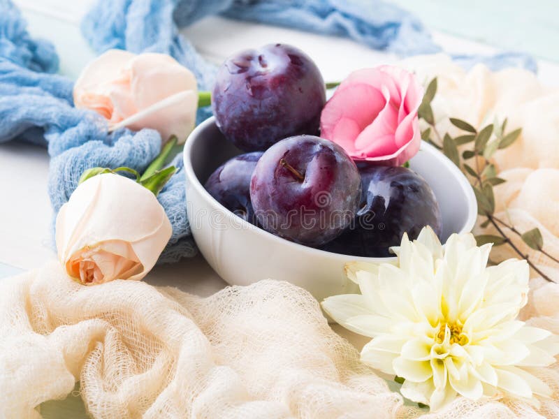 Prunes bleues dans la cuvette avec des fleurs image stock Prunes bleues dans la cuvette avec des fleurs image stock