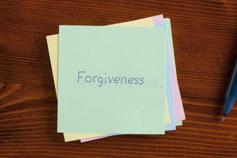 Top view of forgiveness written note on the wooden desk with pen aside. Top view of forgiveness written note on the wooden desk with pen aside.