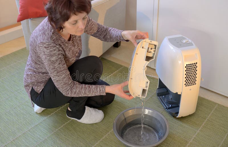 Woman with Portable dehumidifier colect water. Woman with Portable dehumidifier colect water