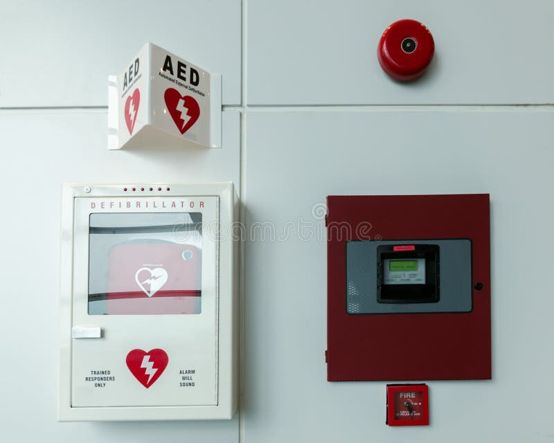 General view of a life saving defibrillator. Portable automated external defibrillator AED and fire alarm system mounted on the wall in public restroom at airport. General view of a life saving defibrillator. Portable automated external defibrillator AED and fire alarm system mounted on the wall in public restroom at airport.