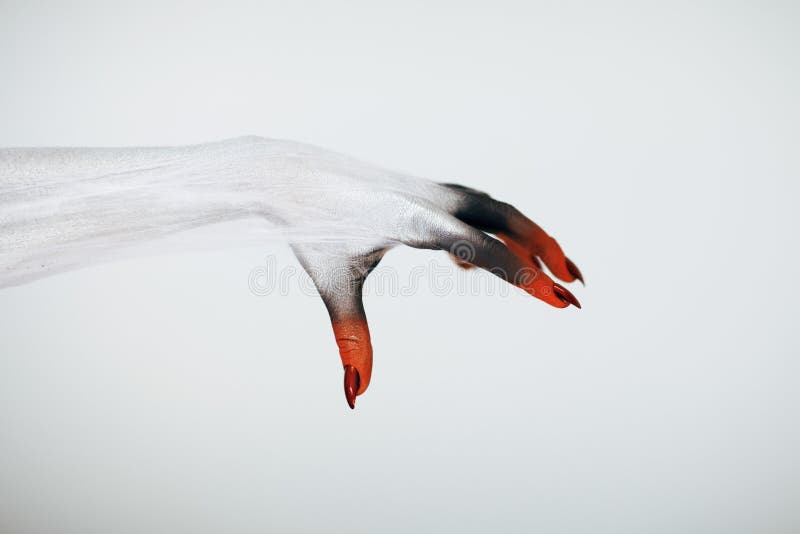 Creepy Halloween monster witch hand with white, red and black make up and long creepy fingernails and spiderweb in front of white background. Creepy Halloween monster witch hand with white, red and black make up and long creepy fingernails and spiderweb in front of white background