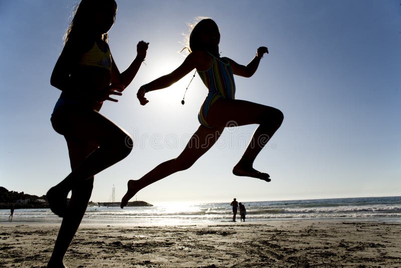 Two girls jumping on the beach, high key image. Two girls jumping on the beach, high key image