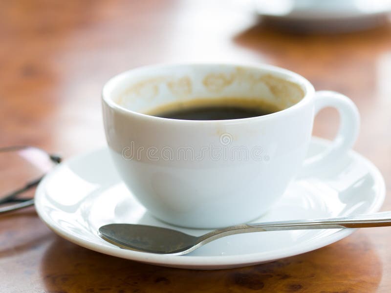 Coffee cups with partly drank coffee and a pair of spectacles on a table top. Coffee cups with partly drank coffee and a pair of spectacles on a table top