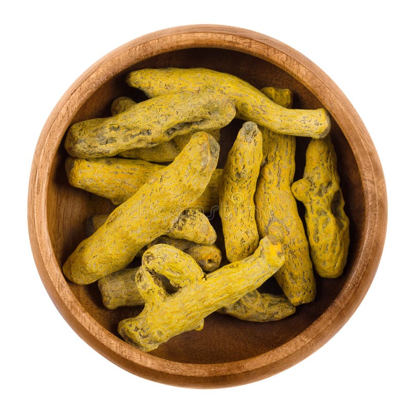 Przetwarzający turmeric kłącza w drewnianym pucharze nad bielem obraz stock Przetwarzający turmeric kłącza w drewnianym pucharze nad bielem obraz stock