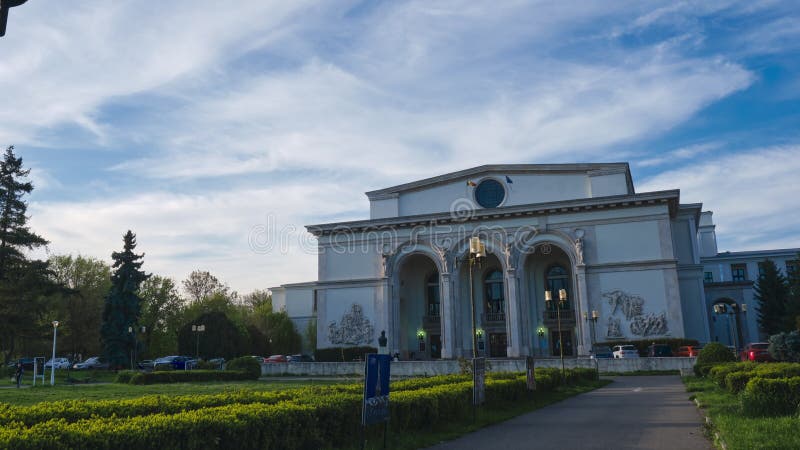 Przewrót krajowego budynku opery w Bukareszcie ukazujący zewnętrzną fasadę i mętne wieczorne niebo.