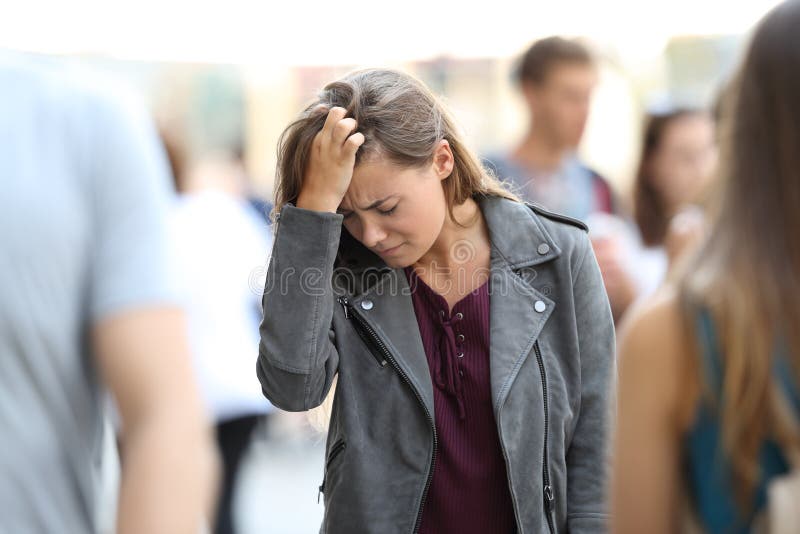 Depressed teen feeling lonely walking on the street surrounded by people. Depressed teen feeling lonely walking on the street surrounded by people