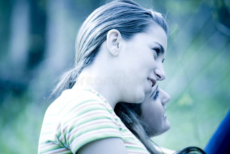 Young women leaning on friends shoulder and smiling. Young women leaning on friends shoulder and smiling.