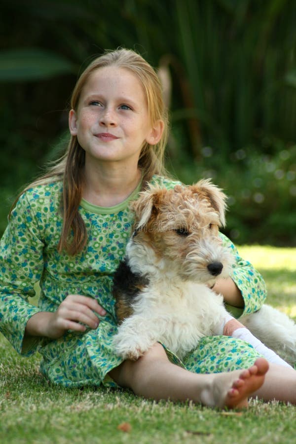 A white Caucasian girl sitting on the grass with her puppy. A white Caucasian girl sitting on the grass with her puppy