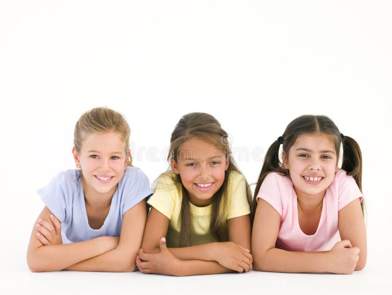 Row of three friends lying down smiling at camera. Row of three friends lying down smiling at camera