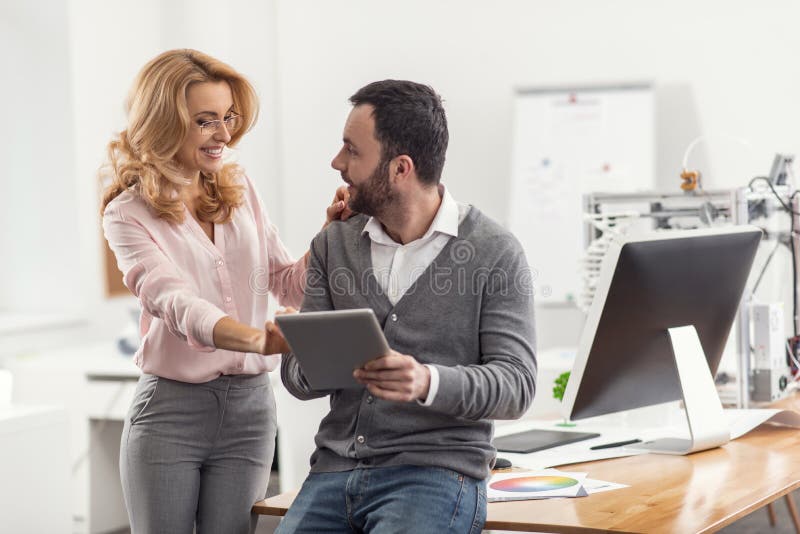 Przyjemna kobieta flirtuje z jej kolegą w biurze obraz stock Przyjemna kobieta flirtuje z jej kolegą w biurze obraz stock