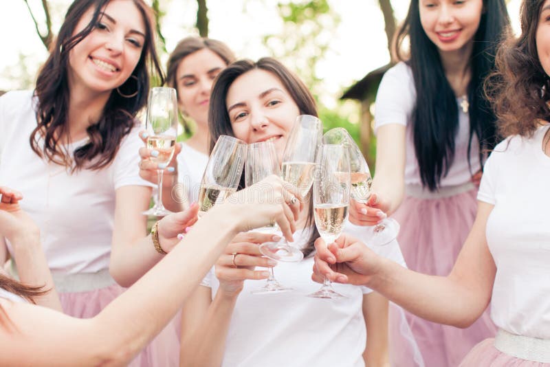 Cropped light photo of happy girls celebrating at bachelorette party outdoor, bride is standing in the middle. Girls holding glasses of champange clinking them together, smiling and cheering. Cropped light photo of happy girls celebrating at bachelorette party outdoor, bride is standing in the middle. Girls holding glasses of champange clinking them together, smiling and cheering